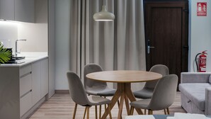 Una cocina moderna con una mesa redonda de madera y sillas grises, una encimera blanca y una lámpara colgante.