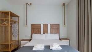 A neatly made bed with a grey quilt, two white pillows, and two folded towels on the bed. - VLC HOST - Reino 6 (Valencia)