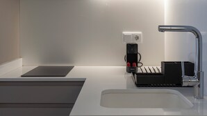 A modern kitchen with a white countertop, a built-in sink, a coffee maker, and a black storage unit. - VLC HOST - Reino 6 (Valencia)