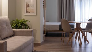 A modern living room with a sofa, a dining table with chairs, a potted plant, and framed artwork on the wall. - VLC HOST - Reino 6 (Valencia)