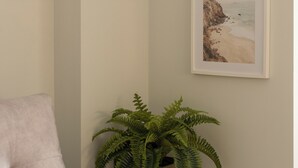 A room with a light-colored sofa, a potted fern, and two framed pictures on the wall. - VLC HOST - Reino 6 (Valencia)