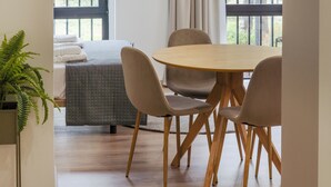 A dining area with a round table and four chairs, a hanging light fixture, and a window with curtains. - VLC HOST - Reino 7 (Valencia)