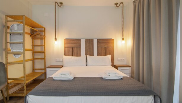 A neatly arranged hotel room with a bunk bed, a bedside table with a lamp, and a large bed with two pillows. - VLC HOST - Reino 7 (Valencia)