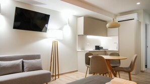 A modern hotel room with a sofa, a bed, a desk, and a dining area. - VLC HOST - Reino 7 (Valencia)