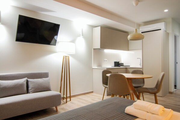A modern hotel room with a sofa, a bed, a desk, and a dining area. - VLC HOST - Reino 7 (Valencia)