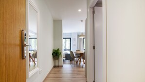 A hallway with wooden flooring, a dining area with a table and chairs, and a potted plant. - VLC HOST - Reino 7 (Valencia)
