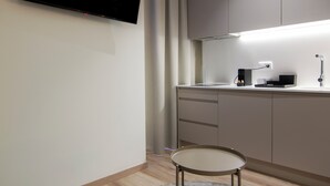 A modern, minimalist room with a flat-screen TV mounted on the wall, a desk with a lamp, and a chair. - VLC HOST - Reino 5 (Valencia)