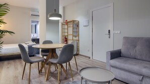 A modern living room with a grey sofa, a round coffee table, and a dining area with a wooden table and grey chairs. - VLC HOST - Reino 5 (Valencia)