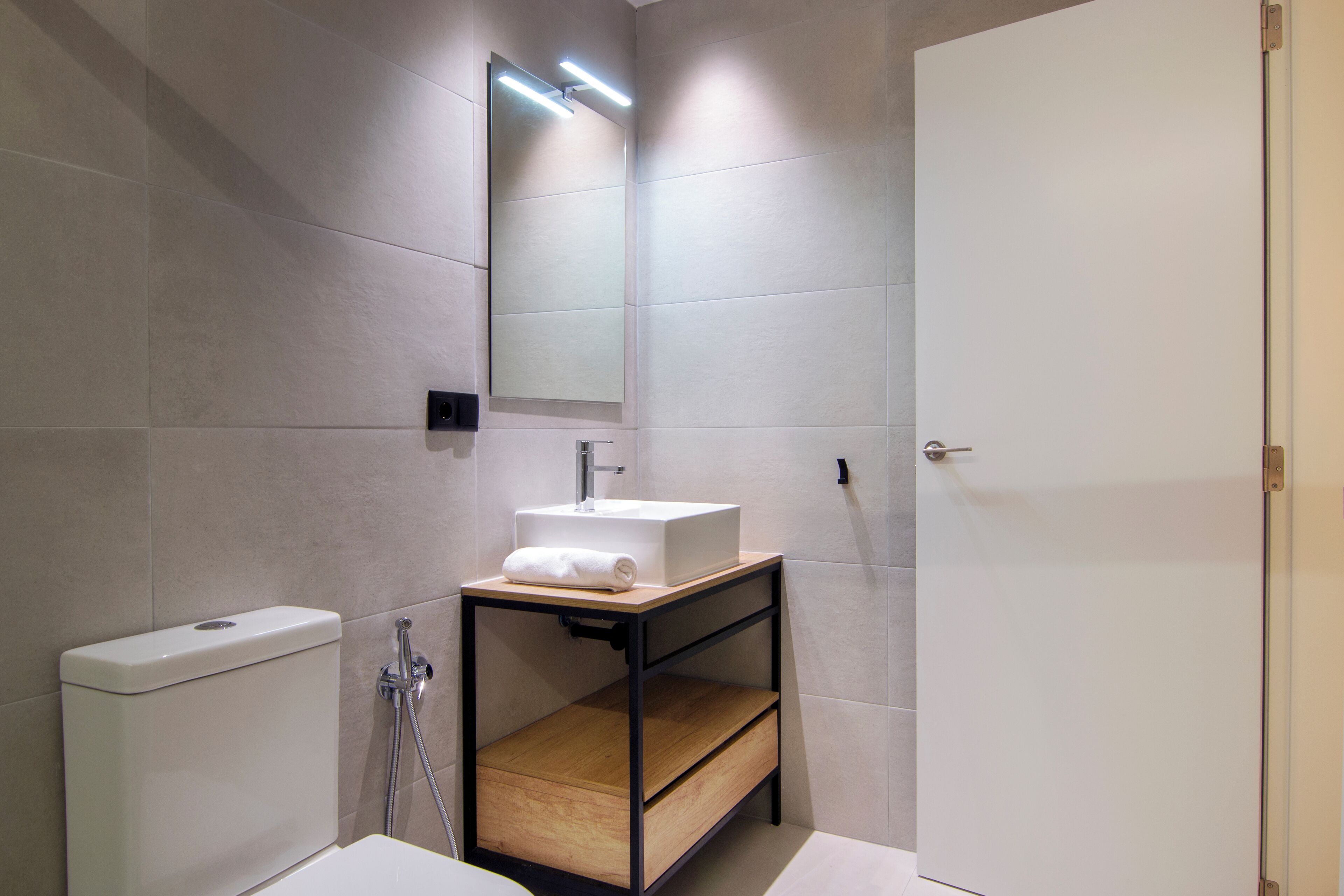 Une salle de bain moderne avec un lavabo blanc, un miroir et des toilettes.
