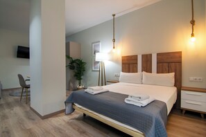 Moderni hotellihuone, jossa on suuri sänky, yöpöydät, työpöytä ja televisio.