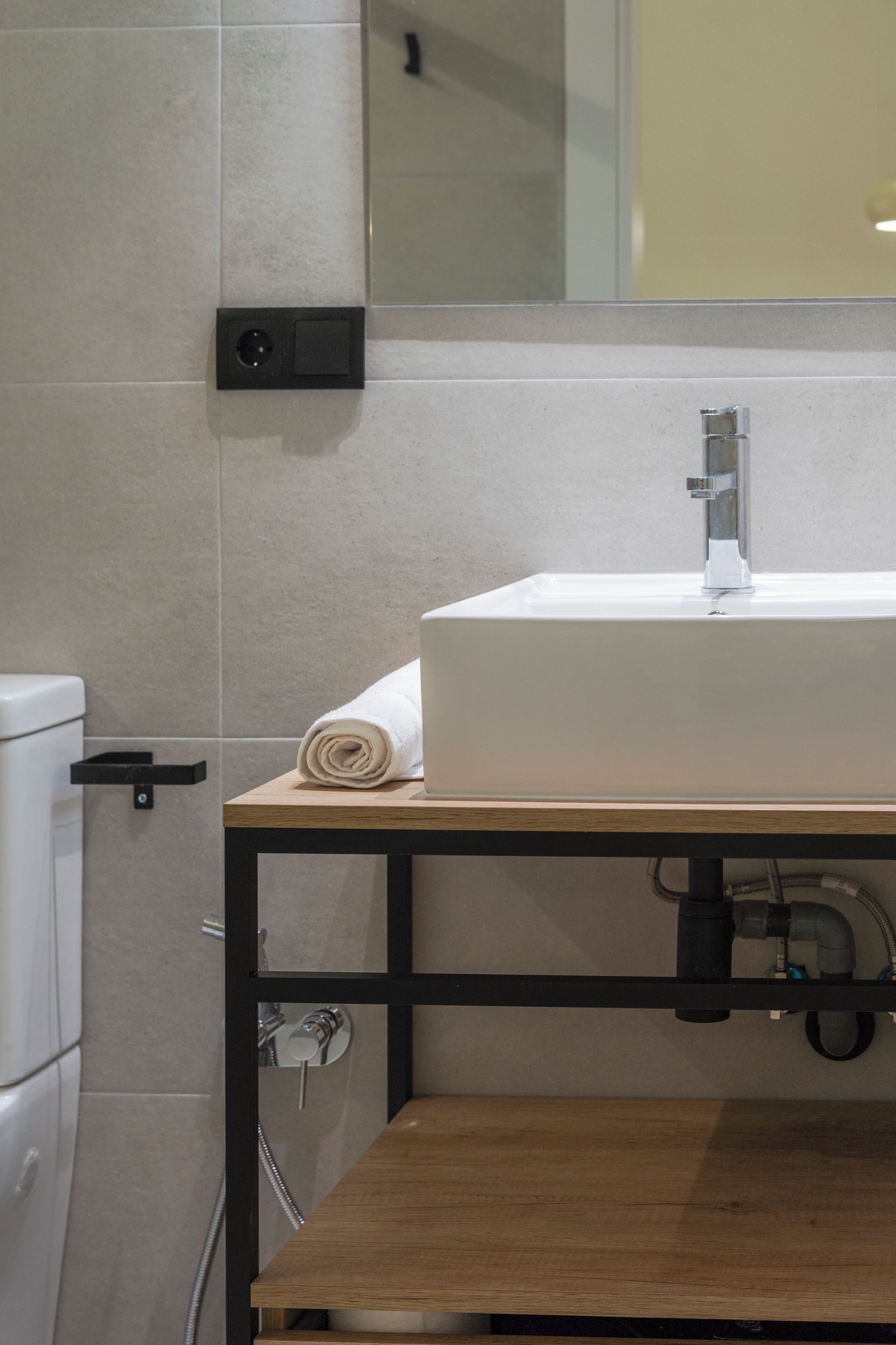 Une salle de bain avec un lavabo blanc, un meuble-lavabo en bois, des toilettes et un miroir.