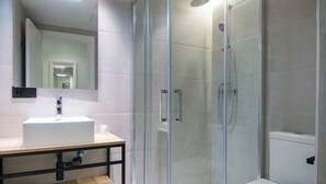Un baño moderno con ducha envuelta en vidrio, un lavabo blanco y un inodoro.