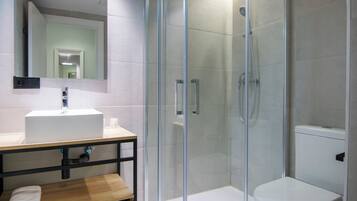 Une salle de bain moderne avec une douche à parois de verre, un lavabo blanc et des toilettes.
