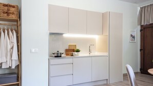 A compact kitchen with white cabinets, a wooden shelf, and a hanging rack. - VLC HOST - Reino 9 (Valencia)