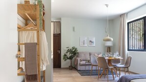 A modern hotel room with a wooden wardrobe, a dining area with a table and chairs, a sofa, and a large window with curtains. - VLC HOST - Reino 9 (Valencia)