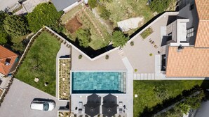 Vue aérienne d’une propriété comprenant une piscine, une voiture et un bâtiment doté d’un toit en tuiles.
