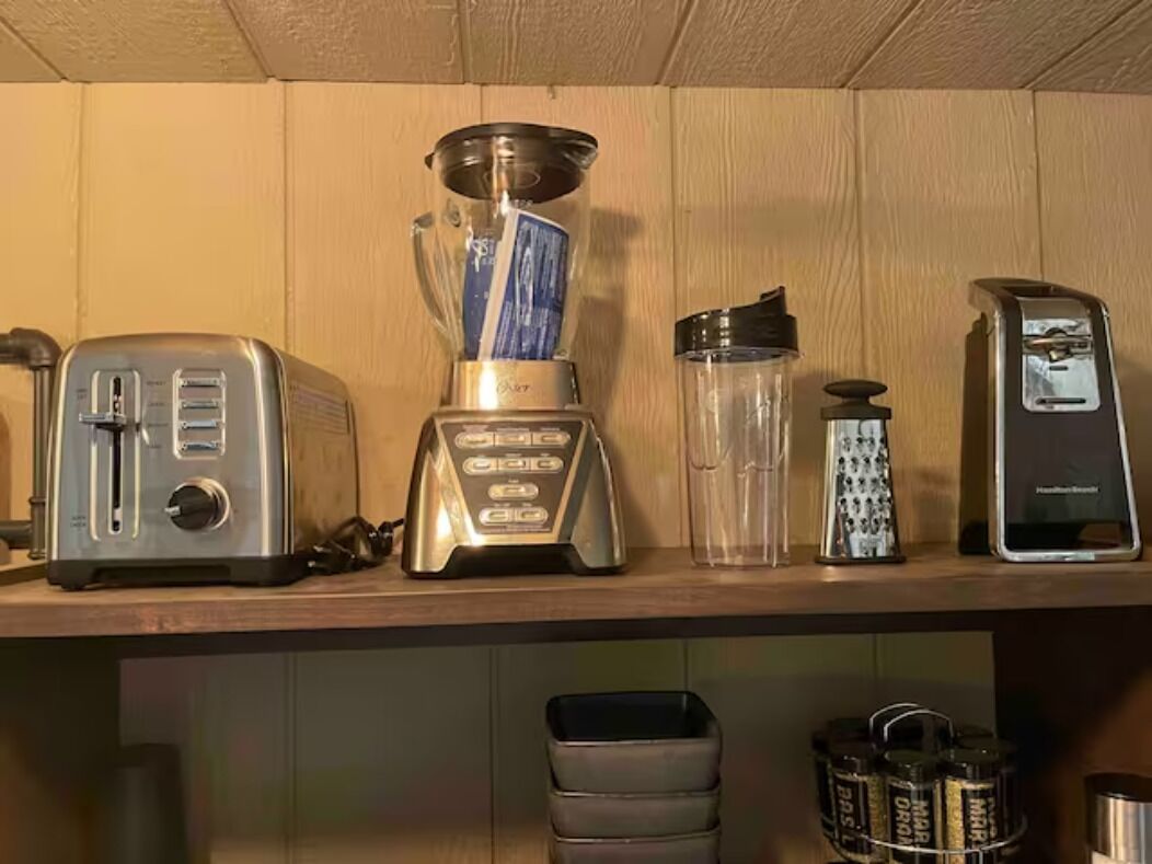 A kitchen counter with a toaster, blender, water bottle, and coffee maker.
