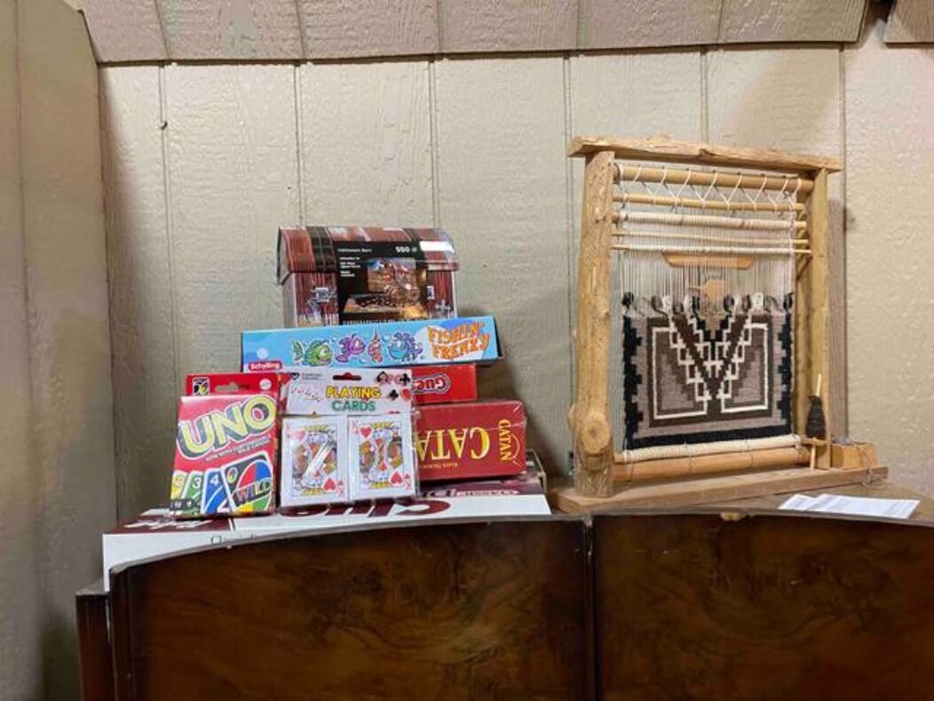 A wooden table with various board games and a framed textile piece.