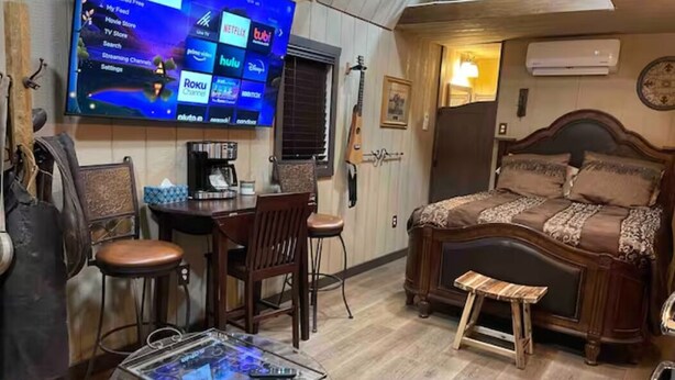Una habitación acogedora con una cama, una mesa de centro, un televisor que muestra servicios de streaming y una silla de madera.