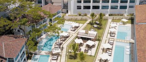 Et resort med flere swimmingpools, liggestole og havudsigt.