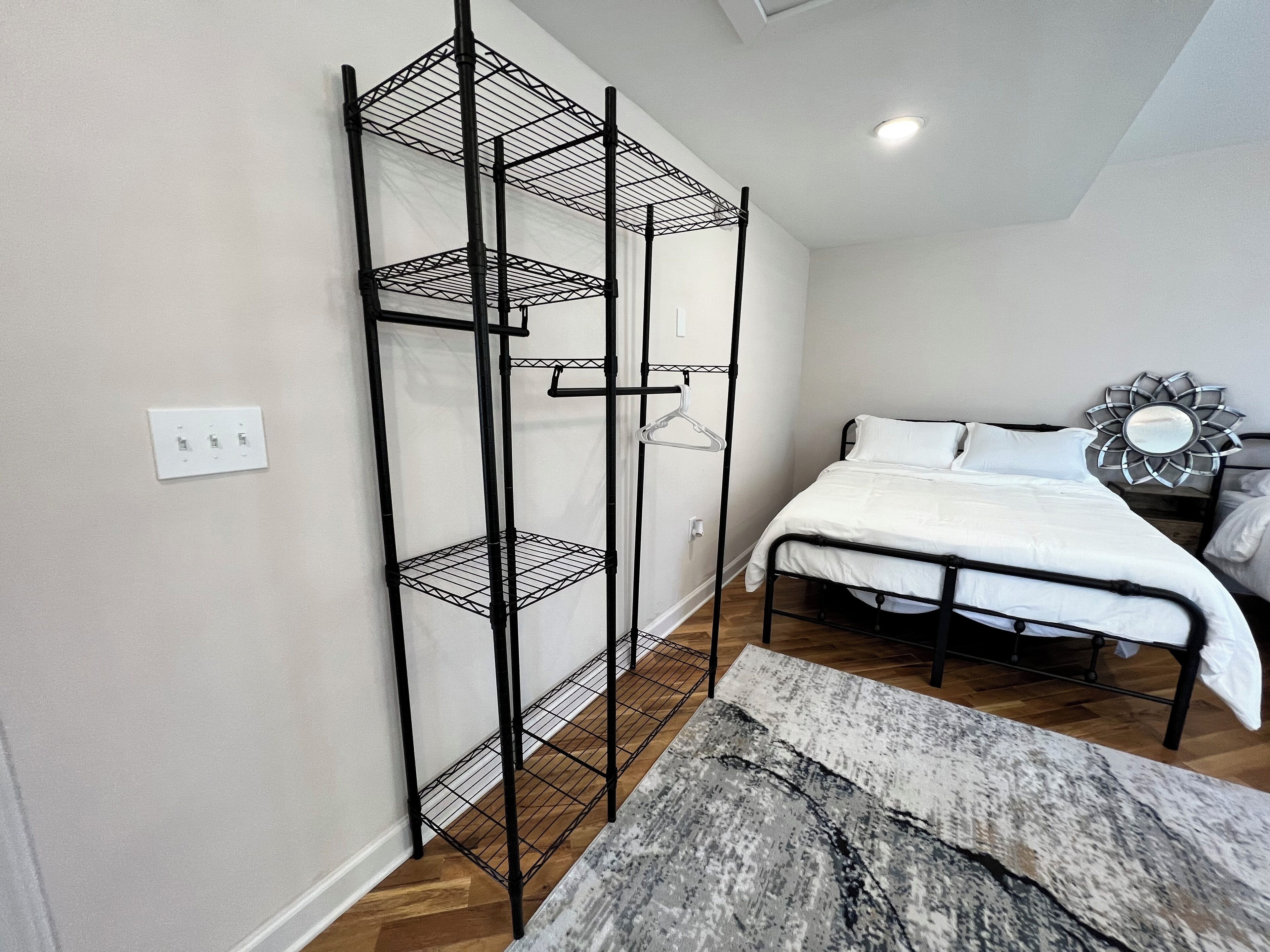 Une chambre avec un lit superposé, une étagère en métal, un banc en bois et un miroir décoratif.