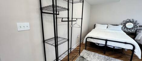 Une chambre avec un lit superposé, une étagère en métal, un banc en bois et un miroir décoratif.