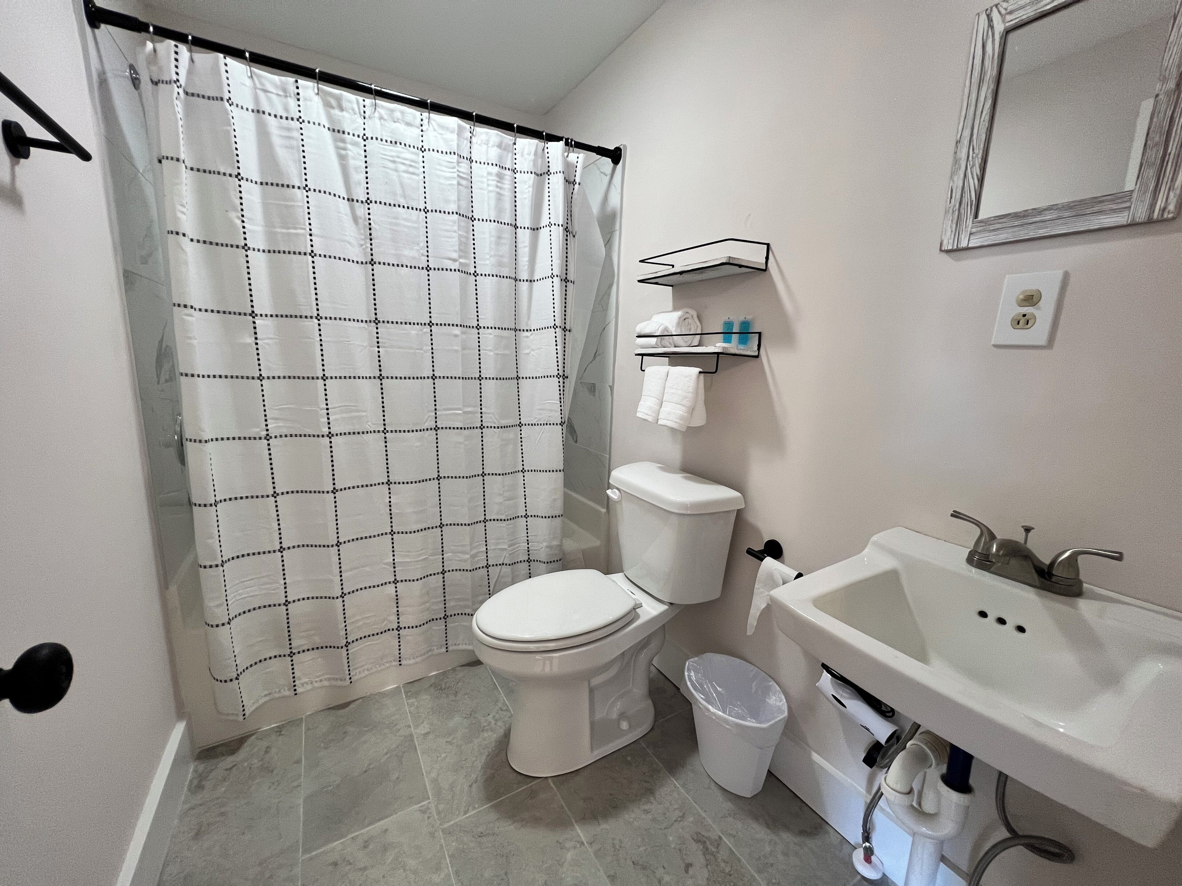 A bathroom with a toilet, sink, and shower curtain.