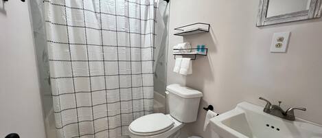 A bathroom with a toilet, sink, and shower curtain.