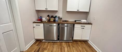 A compact kitchen with white cabinets, stainless steel appliances, and a wooden countertop.