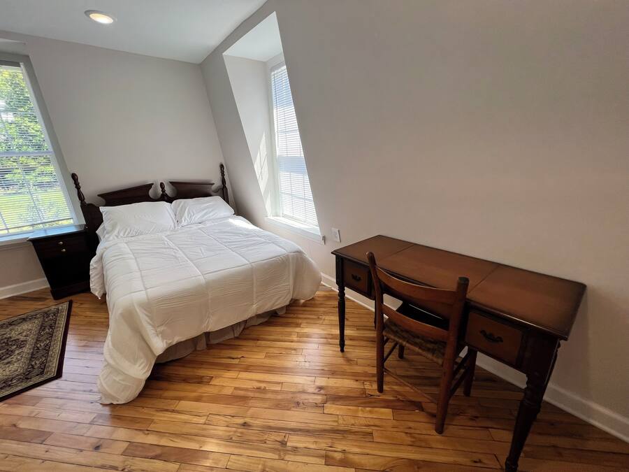 Un dormitorio con una cama, un escritorio de madera y una silla.