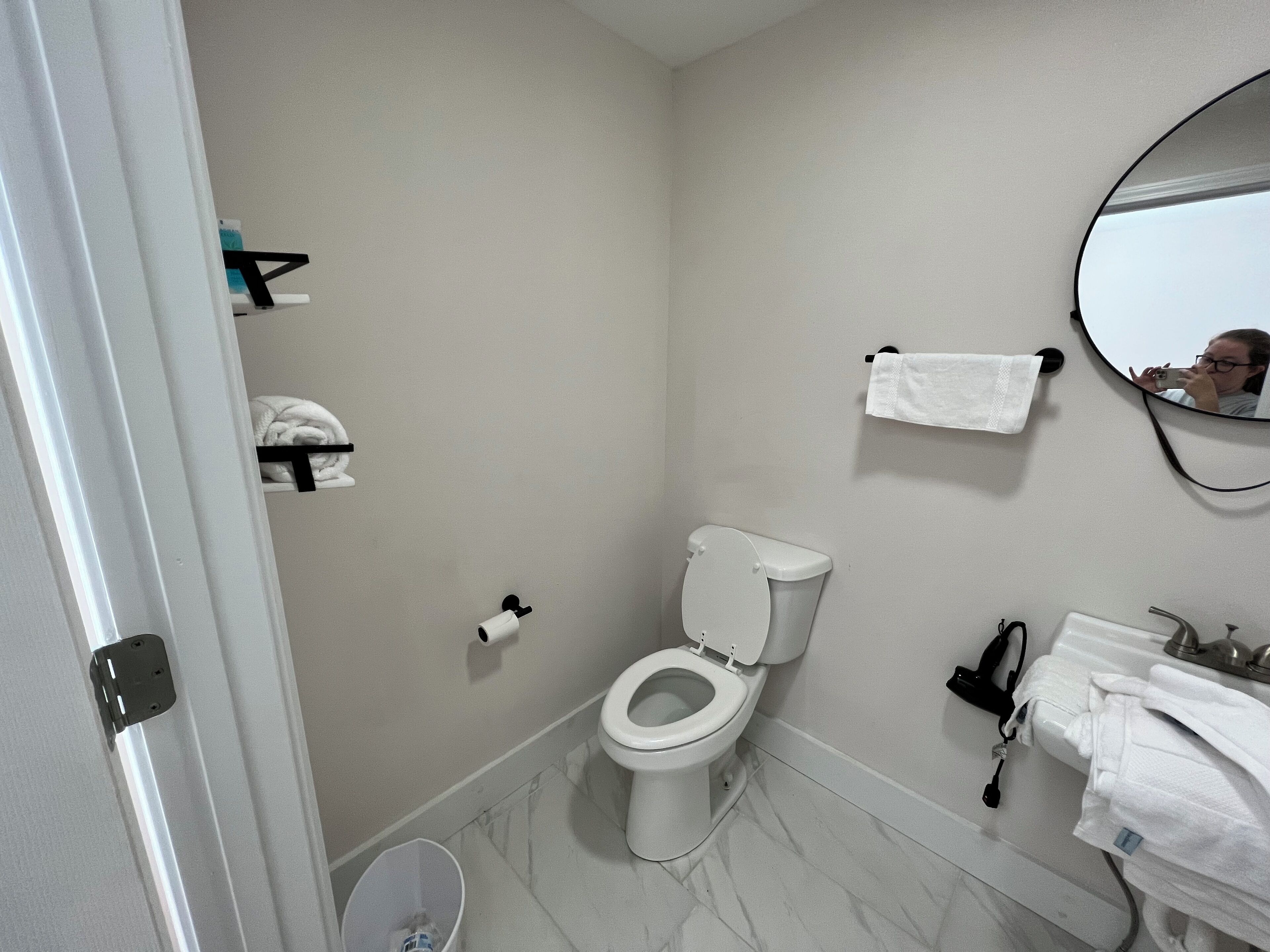 Un baño con inodoro, lavamanos, espejo y toallero.