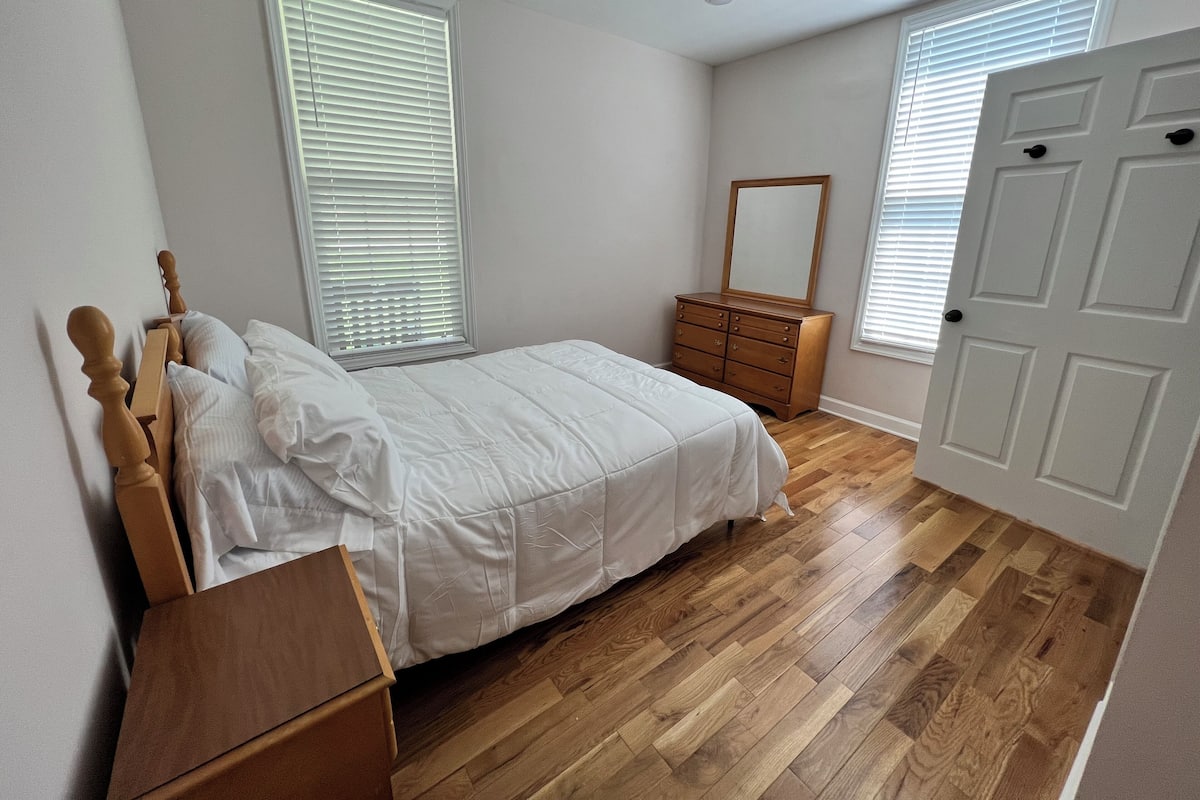 A bedroom with a bed, dresser, and a door.
