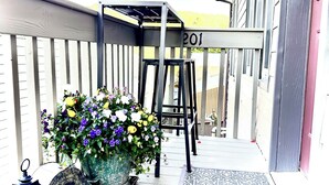 A wooden deck with a metal railing, a hanging flower pot, and a metal bench. - Entire cozy Rollingstone apt in Mississippi Valley, just 10 min from Winona! (Rollingstone)