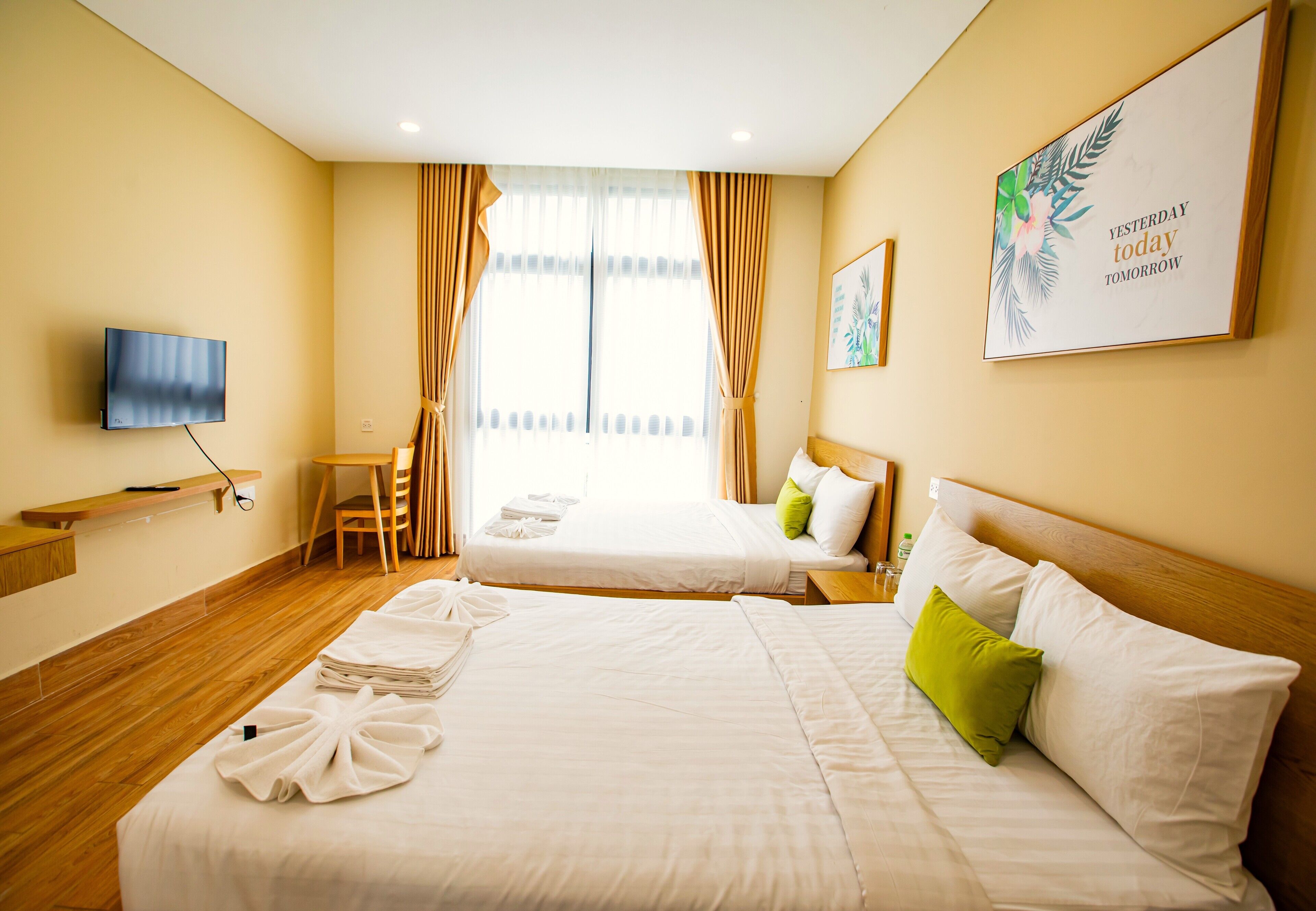 Een hotelkamer met twee bedden, een televisie, een bureau en een raam met gordijnen.