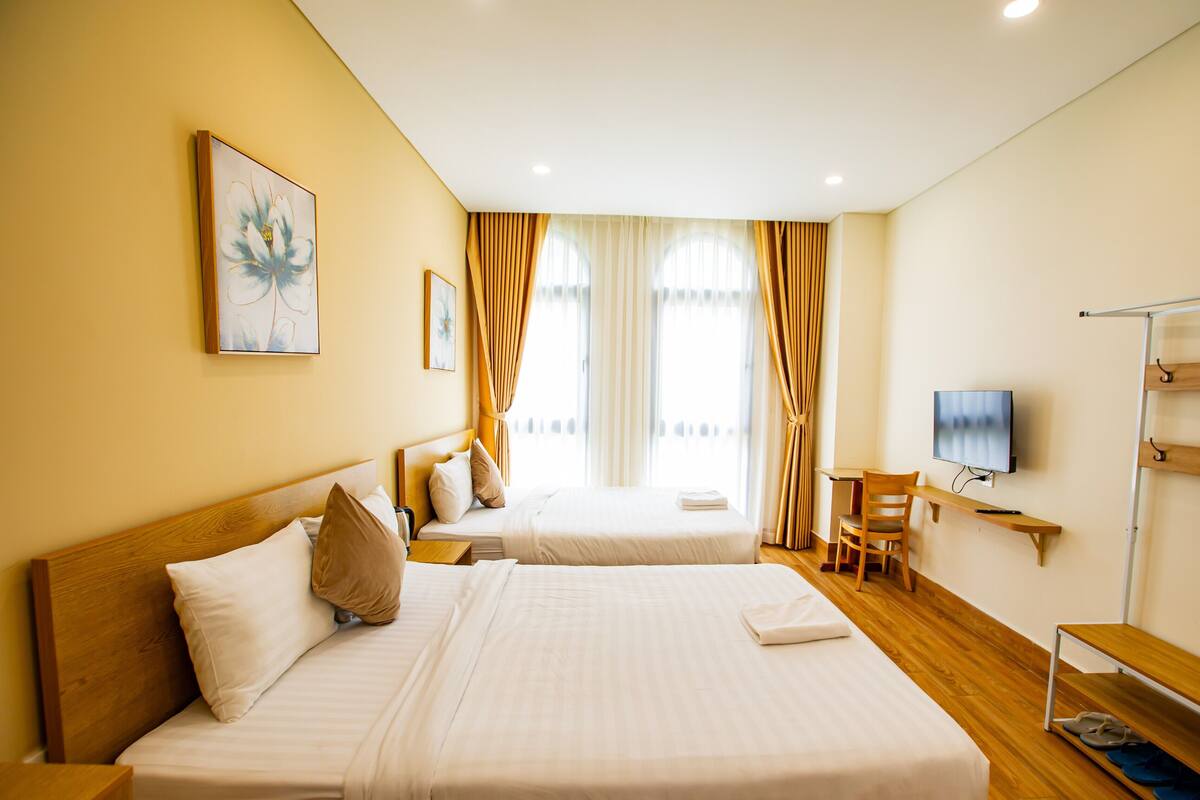 Ein Hotelzimmer mit zwei Betten, einem Fernseher, einem Schreibtisch und einem Stuhl.