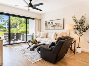 Een moderne woonkamer met een bank, fauteuil en een eethoek met stoelen en een tafel.