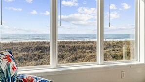 Una habitación con un amplio ventanal con vista a la playa y al océano.