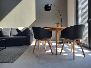 A modern living room with a sofa, two chairs, a wooden table, and a floor lamp.