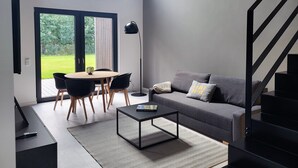 Un salon moderne avec un canapé gris, une table basse et un coin repas comprenant des chaises et une table.