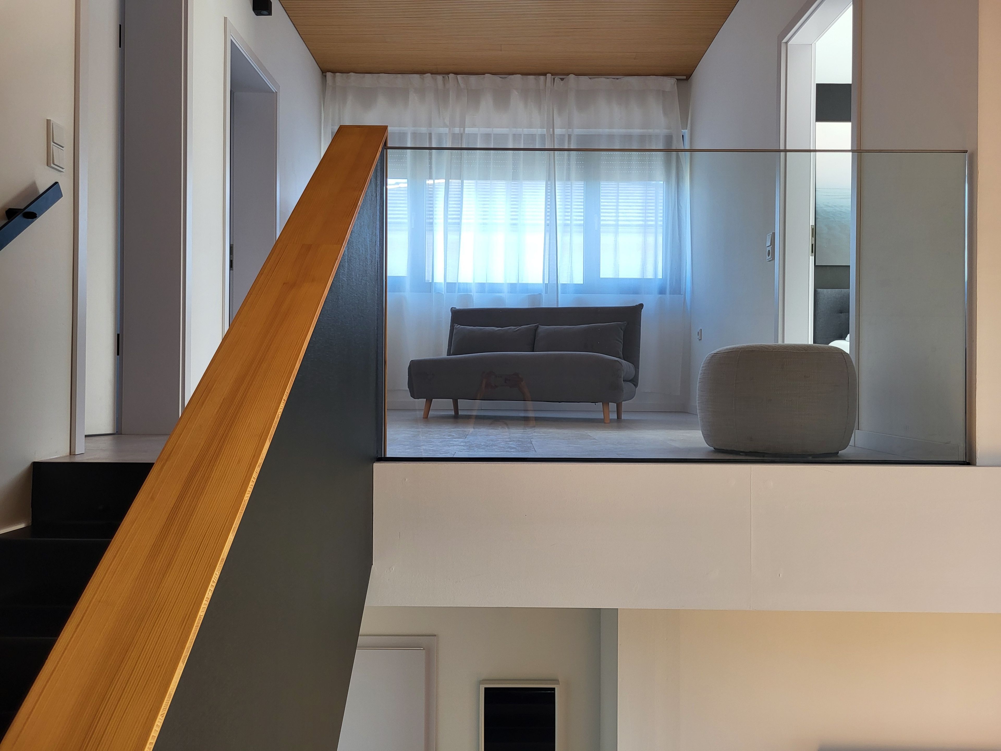 Ein modernes Interieur mit einer Treppe zu einem Wohnbereich, der eine Couch und einen runden Hocker zeigt.