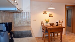 A kitchen with a dining table, chairs, a coffee maker, and a kettle. - Mercyscher Hof Apartment, 70 sqm, 2 Bedrooms, 1 Living Room, up to 6 Guests (Gengenbach)