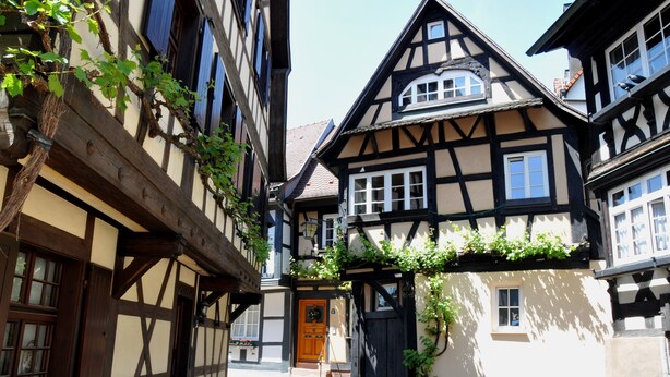 A traditional half-timbered building with a wooden door, a small porch, and a staircase leading to the entrance.