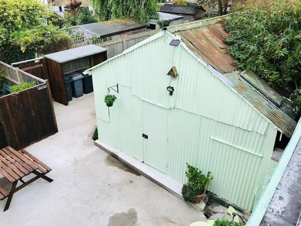 A small, enclosed outdoor space with a concrete floor, a wooden bench, and a corrugated metal shed.
