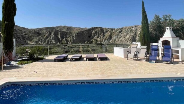 Un espace piscine avec des chaises longues et une vue sur des montagnes rocheuses.