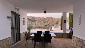 Une terrasse extérieure avec une piscine, des murs en pierre et une vue sur les montagnes.
