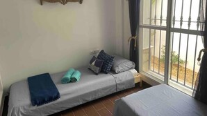 Une petite pièce agréable et chaleureuse, avec un lit simple, un banc et une fenêtre donnant sur l’extérieur.