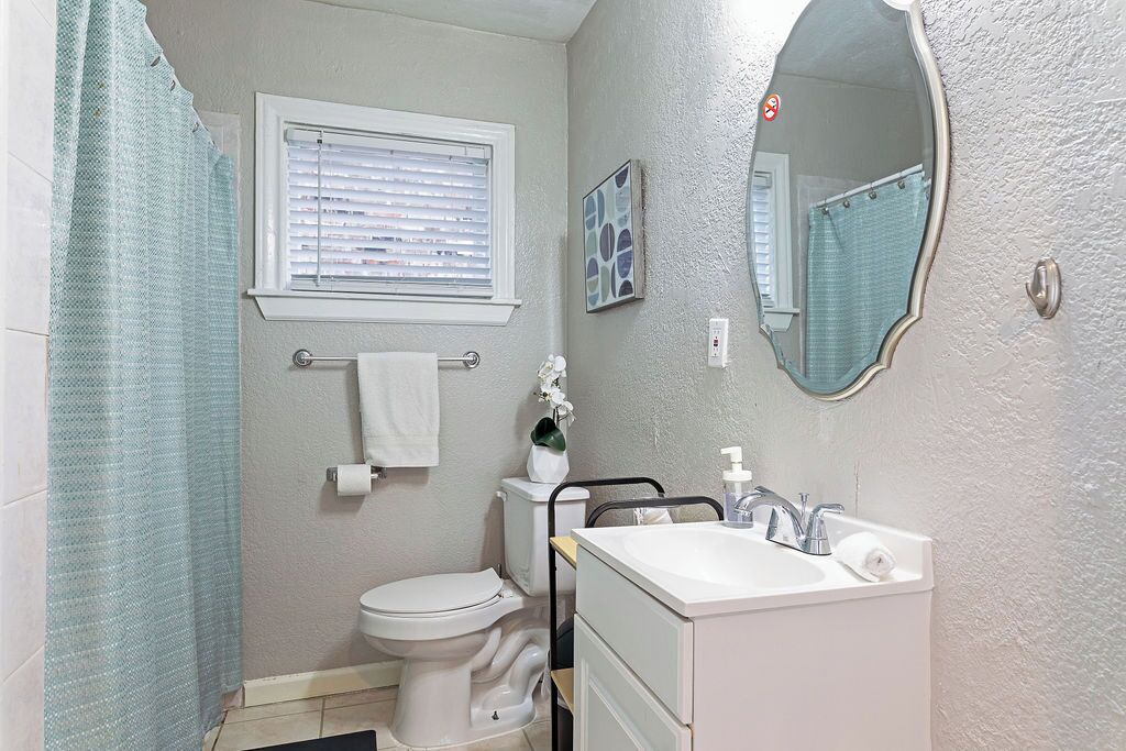 A bathroom with a toilet, sink, and shower curtain.