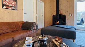 A cozy room with a wooden interior, a sofa, a coffee table with cups and a coffee pot, and a fireplace.