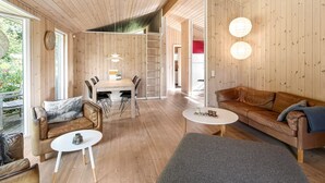 A cozy cabin interior with a wooden floor, a dining area, a sofa, and a coffee table.