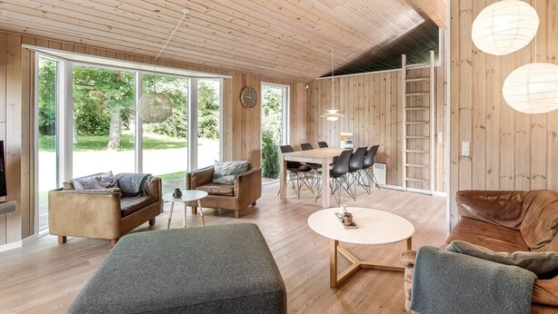 A modern interior with wooden floors, a dining area, and a seating area with a fireplace.
